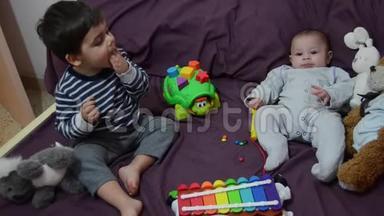 两岁和四个月大的男孩在床上玩木琴和软玩具